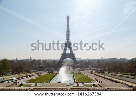 The Eiffel tower in daylight blue sky with some cloud. Champ de Mars park and people in foreground