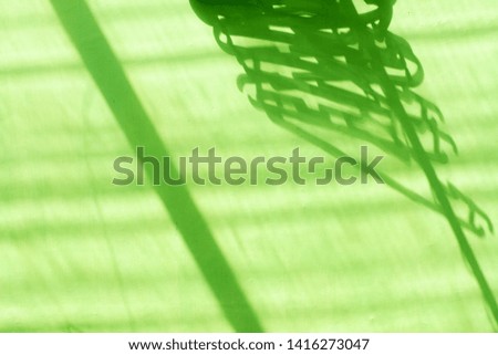 Isolated of clothes hanger shadow on the green background exposed by sunlight in the afternoon. Side view close up details. 