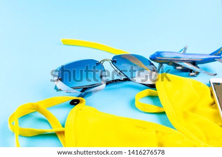 Top view of toy Airplane model, yellow swimsuit and glasses on blue background, picture for add text message or used background, website, travel and tour background Trip Concept