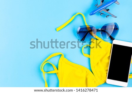Top view of toy Airplane model, yellow swimsuit and glasses on blue background, picture for add text message or used background, website, travel and tour background Trip Concept