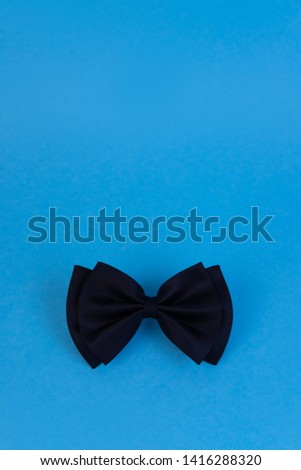 Black bow-tie on blue background with copyspace. Happy fathers day concept. Minimalistic design