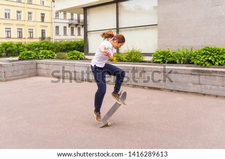 Skater girl jumping ollie in the street. Street culture lifestyle. Sports on a summer day. Women's power.