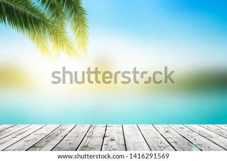 World Oceans Day concept: Empty wooden board on Palm leaves and Abstract blurred  beach with  sunset sky background
