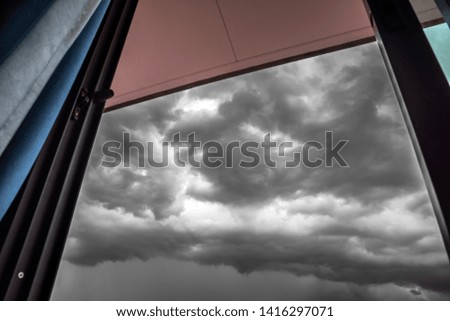 Focus the heavy rain cloud storm, Dark gray rain cloud with blur frame window of the house