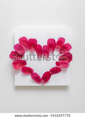 Red juicy  peony petals heart shaped on white background. Copy space, flat lay, minimal concept.