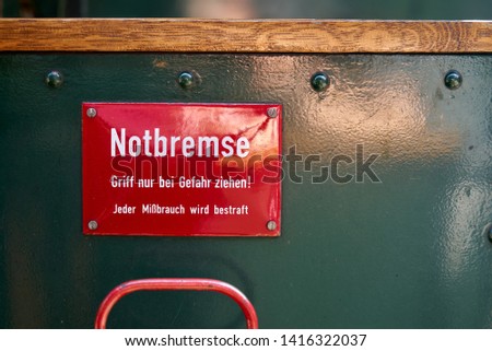 red metal plate with the German text "Notbremse. Nur bei Gefahr ziehen! Jeder Mißbrauch wird bestraft" (translation: emergency brake. Pull only in case of danger! Any misuse will be punished)