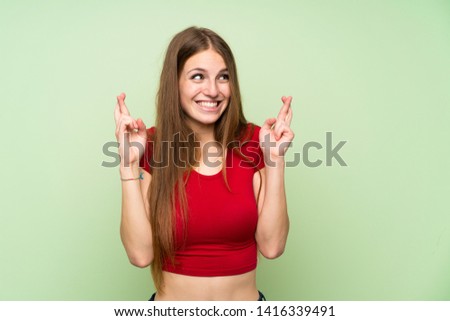 Young woman with long hair over isolated green wall with fingers crossing