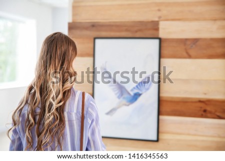 Woman looking at picture of bird in modern art gallery