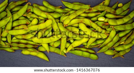 Green soybean pods on dark background. Edamame, close up. Green soy pods, beans on black stone slate surface. Green Soy on black background. Soybean on black slate,  copy space, text place, banner
