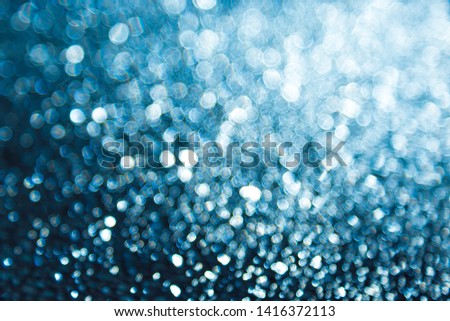 Abstract background with bokeh blurred lights. Shimmering bright blue sequins on a dark background. The picture creates and accentuate a festive magical mood. New year, Christmas, Valentine's day.