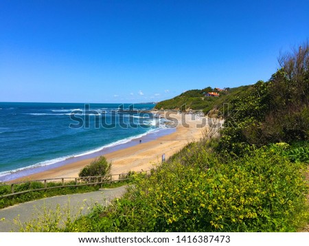 Curved sandy beach with waves on west coast of France. With clear blue sky Royalty-Free Stock Photo #1416387473