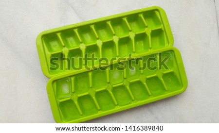 green ice tray with ice cube on white background 