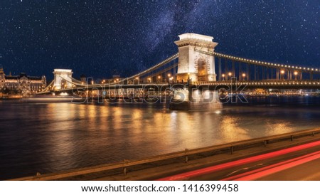 Stunning Chain bridge (Szechenyi lanchid) in night Budapest across the Danube river with city lights and starry sky, cityscape suitable for cover or desktop background Royalty-Free Stock Photo #1416399458