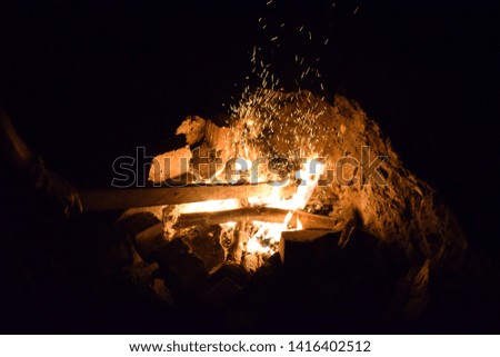 Campfire at night. Flame and fire sparks  on dark abstract background.