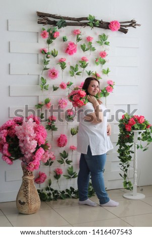 Cute fat girl in jeans and a white T-shirt, posing in the studio with a bright beautiful bouquet of asters. Bright and juicy portrait of a positive girl