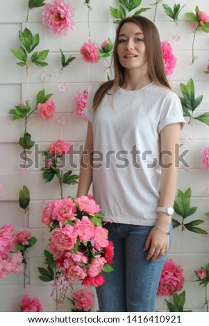 cute blond girl in white T-shirt, posing in the studio with a bright beautiful bouquet of asters. Bright and juicy portrait of a positive girl