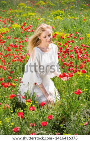 Portrait of young woman  in white dress posing  in poppies plant outdoor