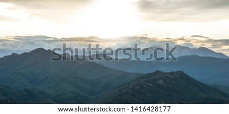 Mediterranean landscape, forest mountains and a screen in the lower part, with sun rays illuminating the image, feeling calm