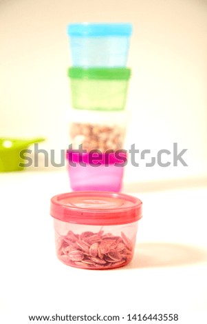Transparent small cookie storage containers on the kitchen table composition made by different alternative next to the tea core nuts in peanut chips plastic colorful caps compasses home decoration.