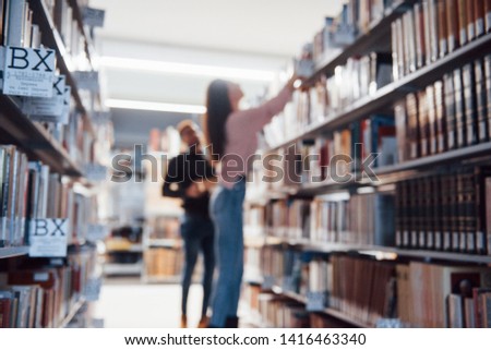 Blurred photo. Multiracial students in the library searching for the information together.
