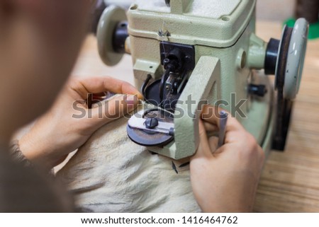 Professional male skinner, furrier using special sewing machine for stitching fur skin at atelier, workshop. Fashion and leatherwork concept