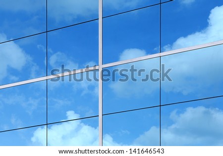 Glass building wall with reflection of clouds
