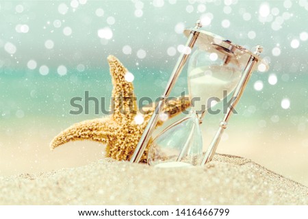 Hourglass and seastar on sandy beach
