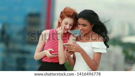 Two young multiracial women looking at cellphone screen