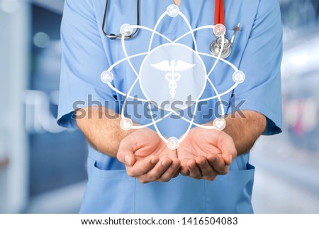 A doctor is operating with the total medical service system scheme hanging at touch screen at the blurred background. The concept of compound medical service system.
    
    - Image