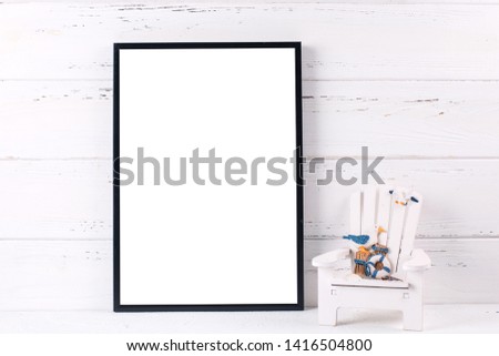Black  frame mockup  with copy space and sea vacation  decorations by  wooden white wall. Portrait orientation.
