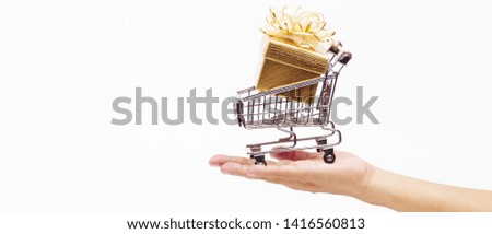 Hand holding a cart carrying a golden gift box on a white background