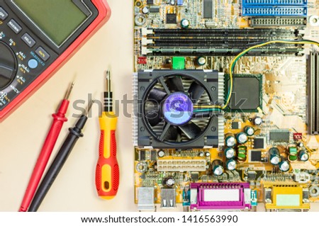 Closeup image of computer main board with screwdriver and digital multimeter. Maintenance  and repair computer hardware  service concept. Top view.