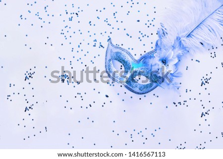 Carnival mask on blue background with sparkles. Festive backdrop for projects. Close-up. Copy space