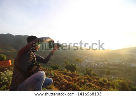 young photographer is taking pictures using a camera under the sun