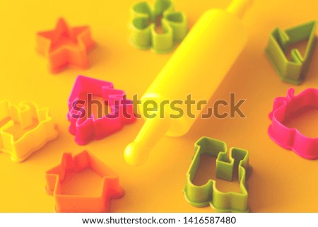 A selective focus shot of color plastic cookie cutters and a rolling pin composed for concept of children activity. 