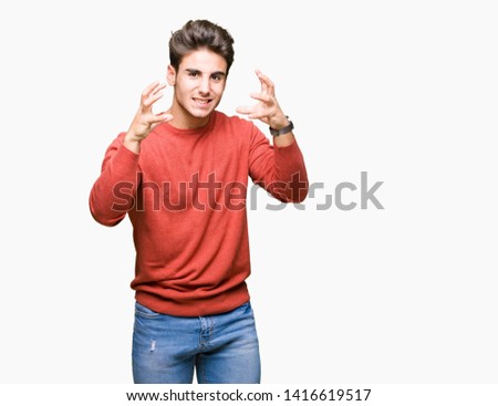 Young handsome man over isolated background Shouting frustrated with rage, hands trying to strangle, yelling mad