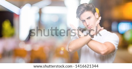 Young handsome man wearing white t-shirt over isolated background Rejection expression crossing arms doing negative sign, angry face