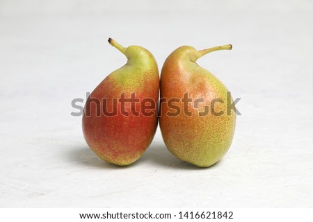  Ugly vegetables , two ripe pears of bizarre shape ,are leaning .  on a white background . the fruits are like penguins .