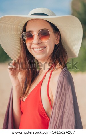 Woman in red bikini smiling at beach.