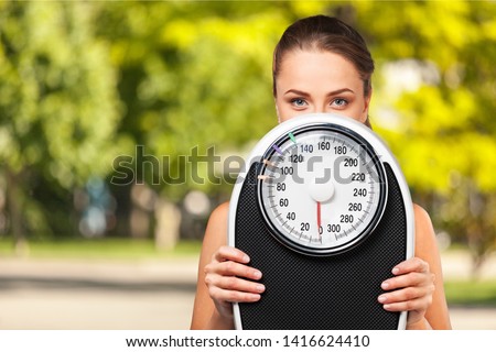 Beautiful young s woman holding scales Royalty-Free Stock Photo #1416624410