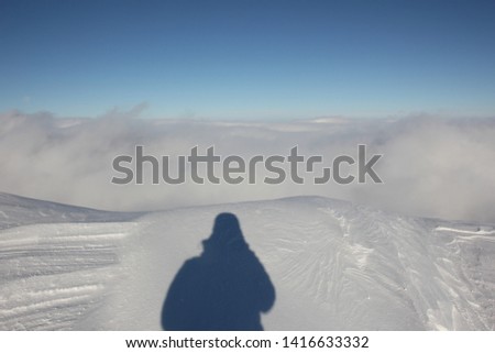 blue sky, clouds, snow and the shadow of the photographer in the mountains. Khibiny, Kola Peninsula.