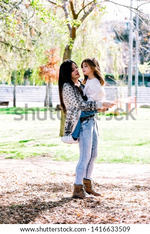 Mom holding her daughter and playing around the park on beautiful morning