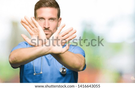 Handsome doctor man wearing medical uniform over isolated background Rejection expression crossing arms and palms doing negative sign, angry face
