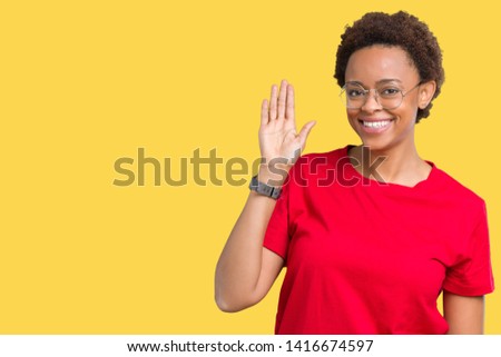 Beautiful young african american woman wearing glasses over isolated background Waiving saying hello happy and smiling, friendly welcome gesture
