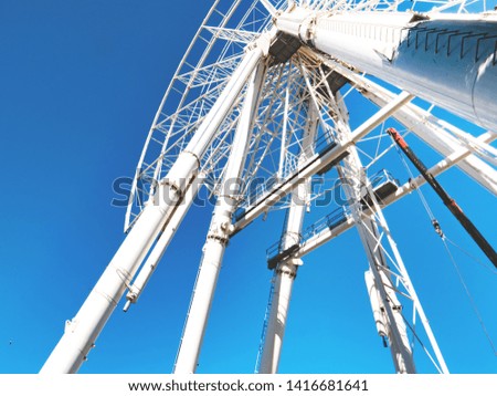 Down view of big Ferris wheel partially disassembled. Cabins and part of the structure have been removed. Blue sky