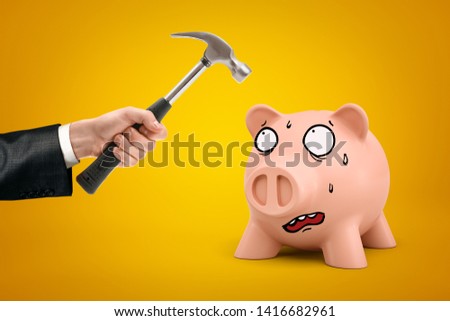 Male hand holding hammer over pink cartoon face piggy bank on yellow background. Business and finance. Management and investment. Income and commerce.