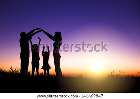 happy family making home sign on the hill with sunrise background