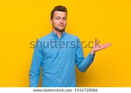 Blonde man over isolated yellow wall making doubts gesture
