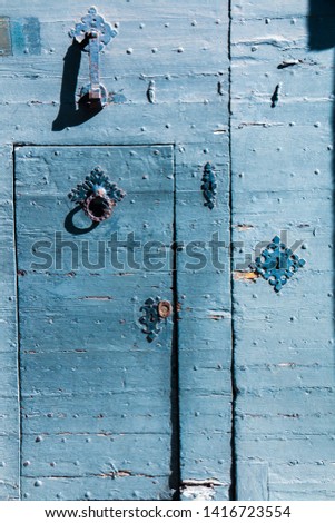 A blue old wooden door with a handle entrance; macro; italian architecture