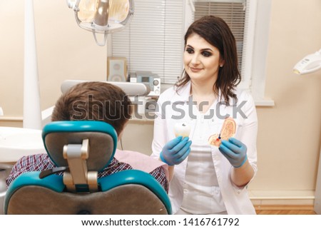 Picture of young female dentist in white coat working with male patient in the dental room.